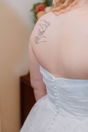 Close-up detail of white wedding dress buttons and back tattoo.