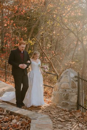 Couple walking along stone path surrounded by autumn foliage.