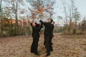 Playful wedding couple dancing and twirling among fall leaves on a mountain overlook.