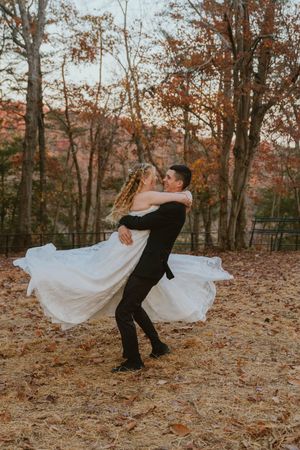 Wedding couple performing dramatic dips and dance moves on fallen autumn leaves.