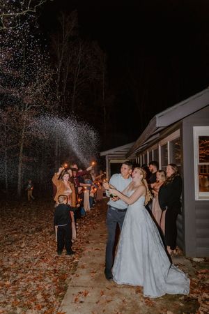 Wedding party spraying champagne at night surrounded by autumn leaves.