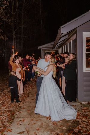 Nighttime wedding party celebration with sparklers and dancing outside a venue.