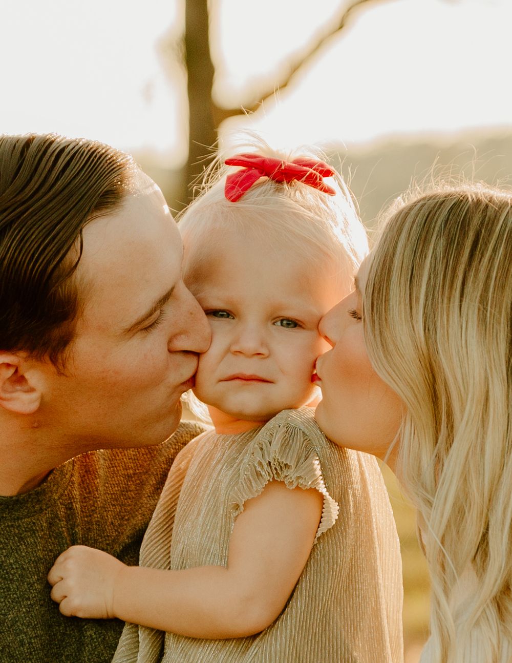 Sweet family cuddles and kisses during sunset photoshoot in nature.