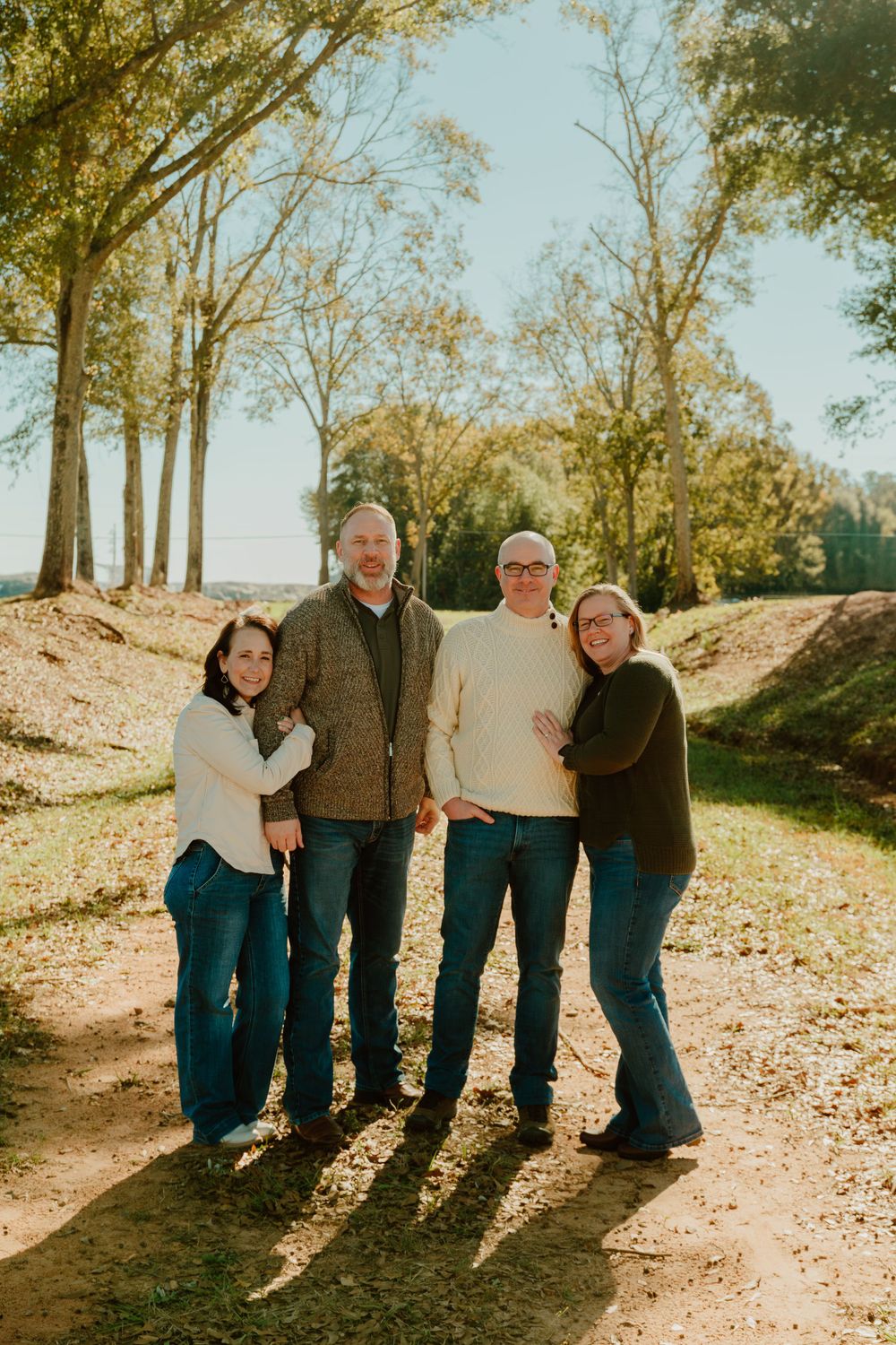 Family members pose together on a hillside covered in fallen autumn leaves.