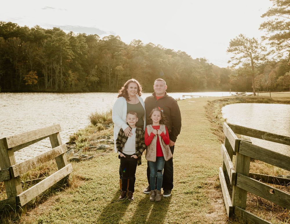 Family enjoying a sunset walk along a lakeside path with golden light filtering through trees.