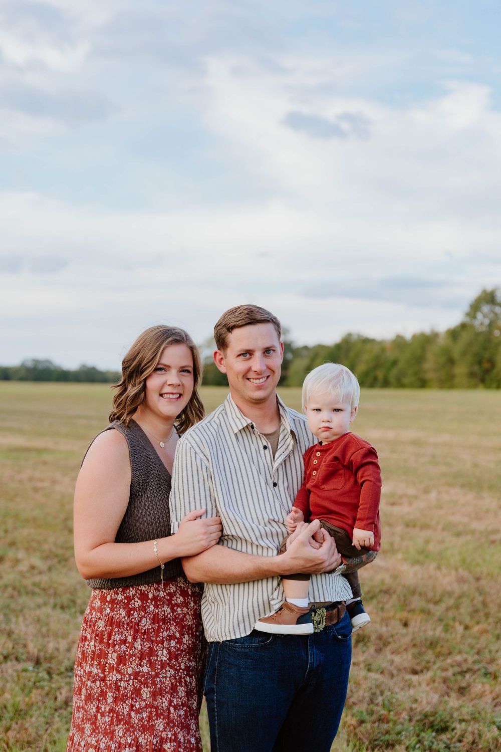 Family portrait session in a rustic field under cloudy skies.