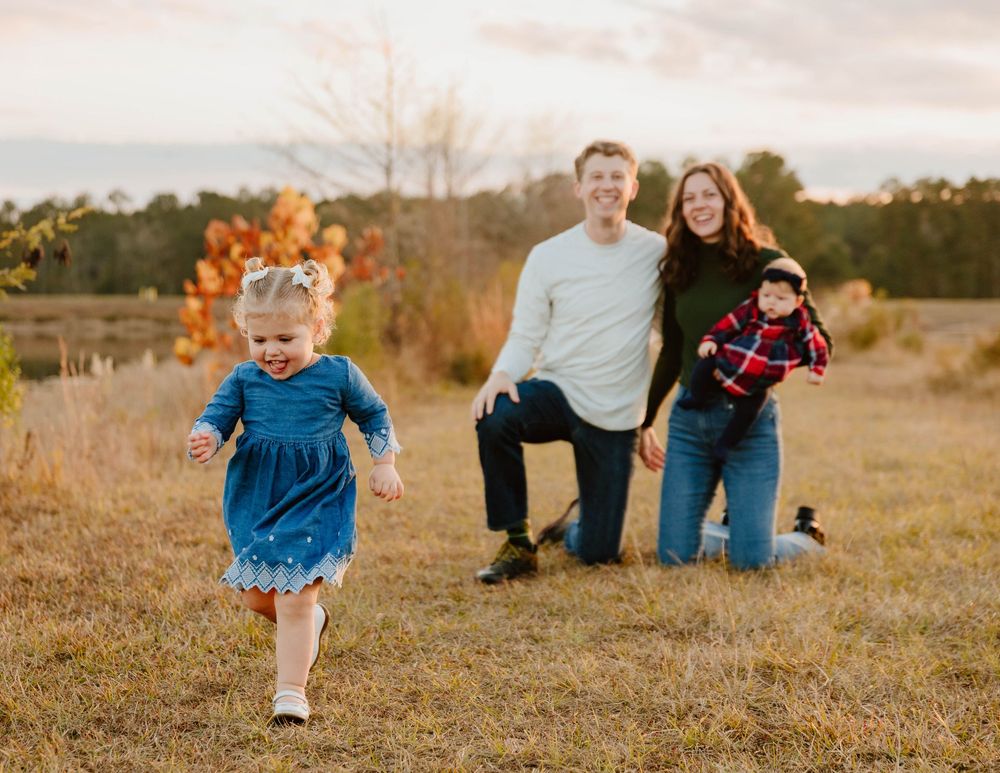 Family playing and running together in a golden autumn field at sunset.