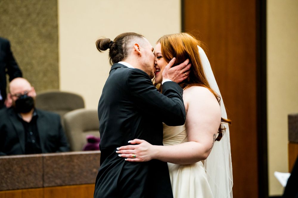 A tender kiss shared during wedding ceremony in an official space.