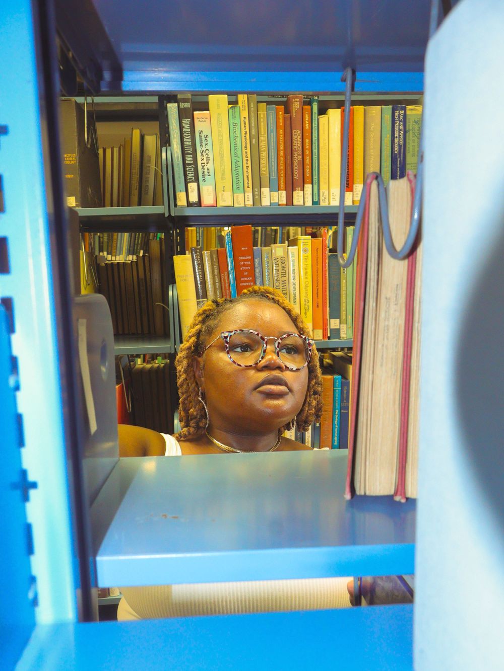 Books on library shelves with a reflection in blue lighting.