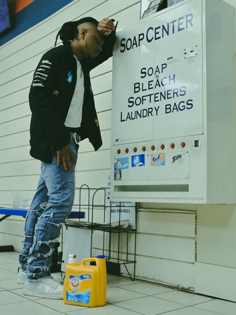 Interior of a laundromat showing soap dispensers and softener stations mounted on white walls.
