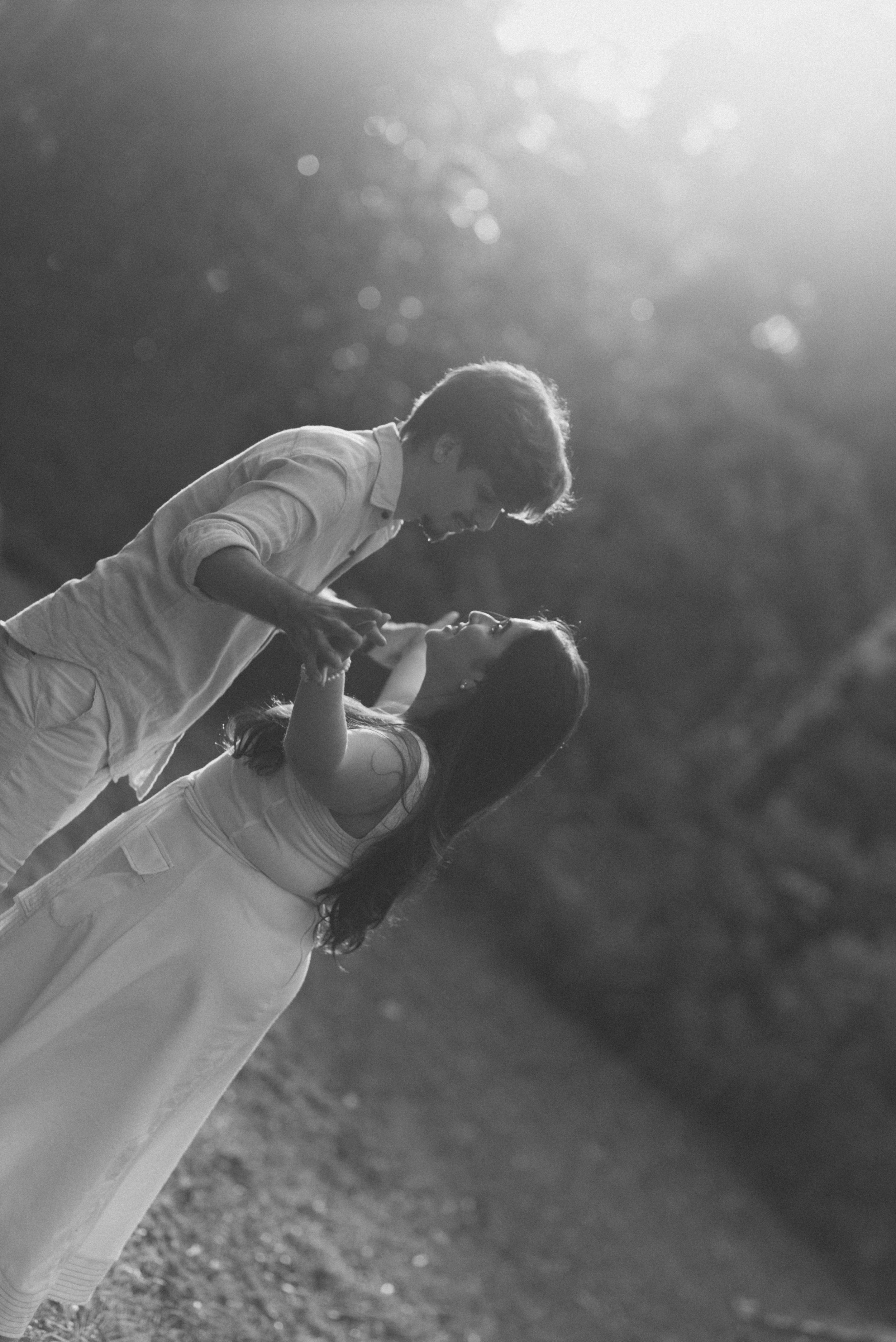 A black and white photo of a couple in an intimate dance pose outdoors.