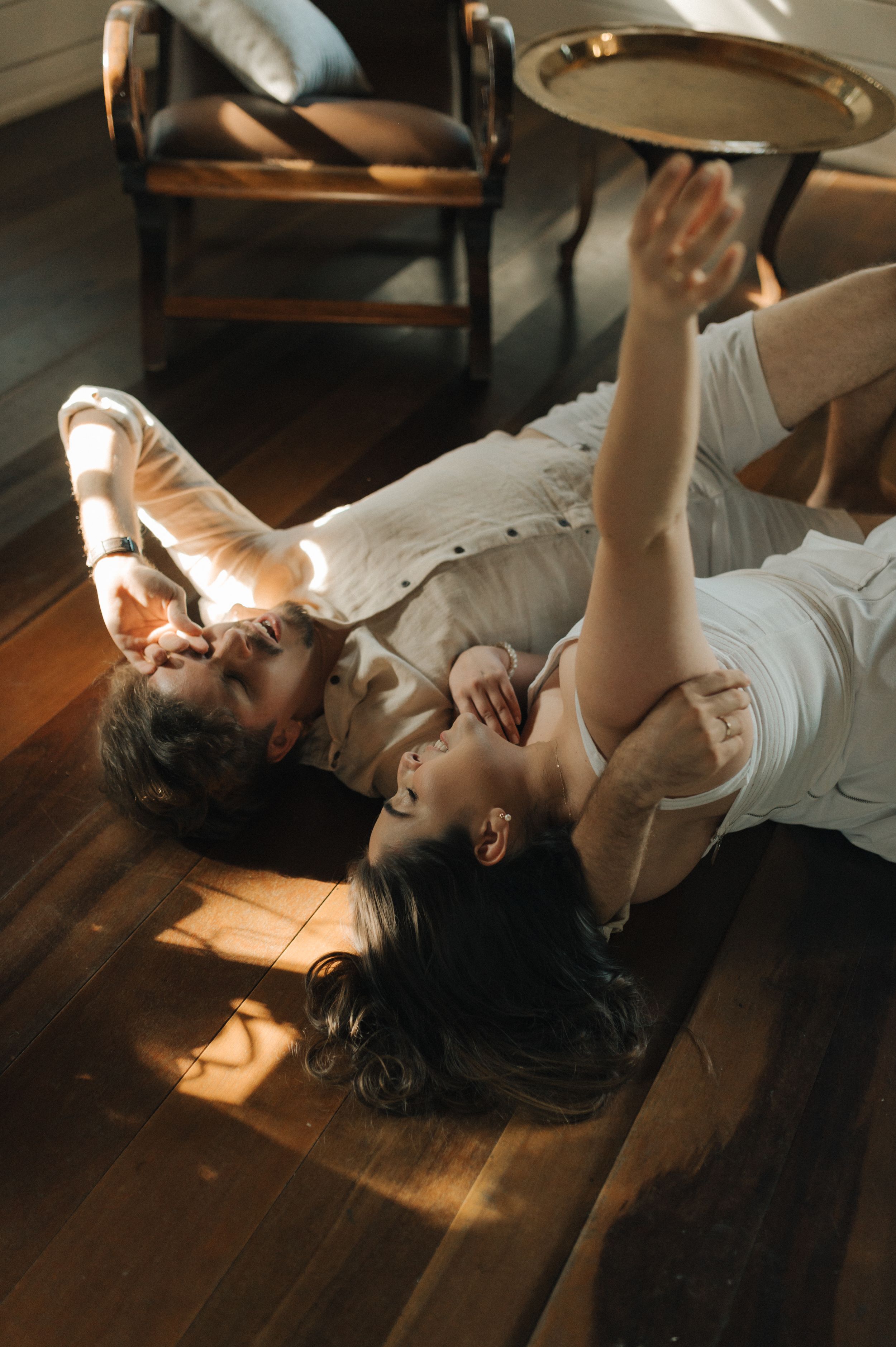Couple relaxing on wooden floor in warm sunlight reaching towards the ceiling.