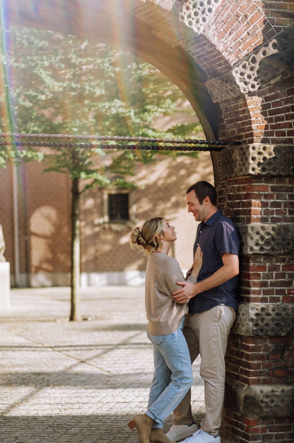 A romantic moment under a brick archway as a couple shares an intimate gaze.