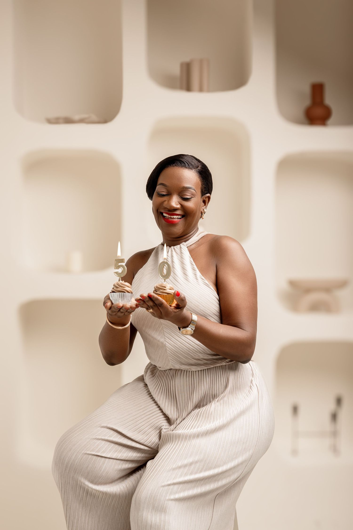 A lifestyle portrait in white attire holding refreshments against a minimalist background.