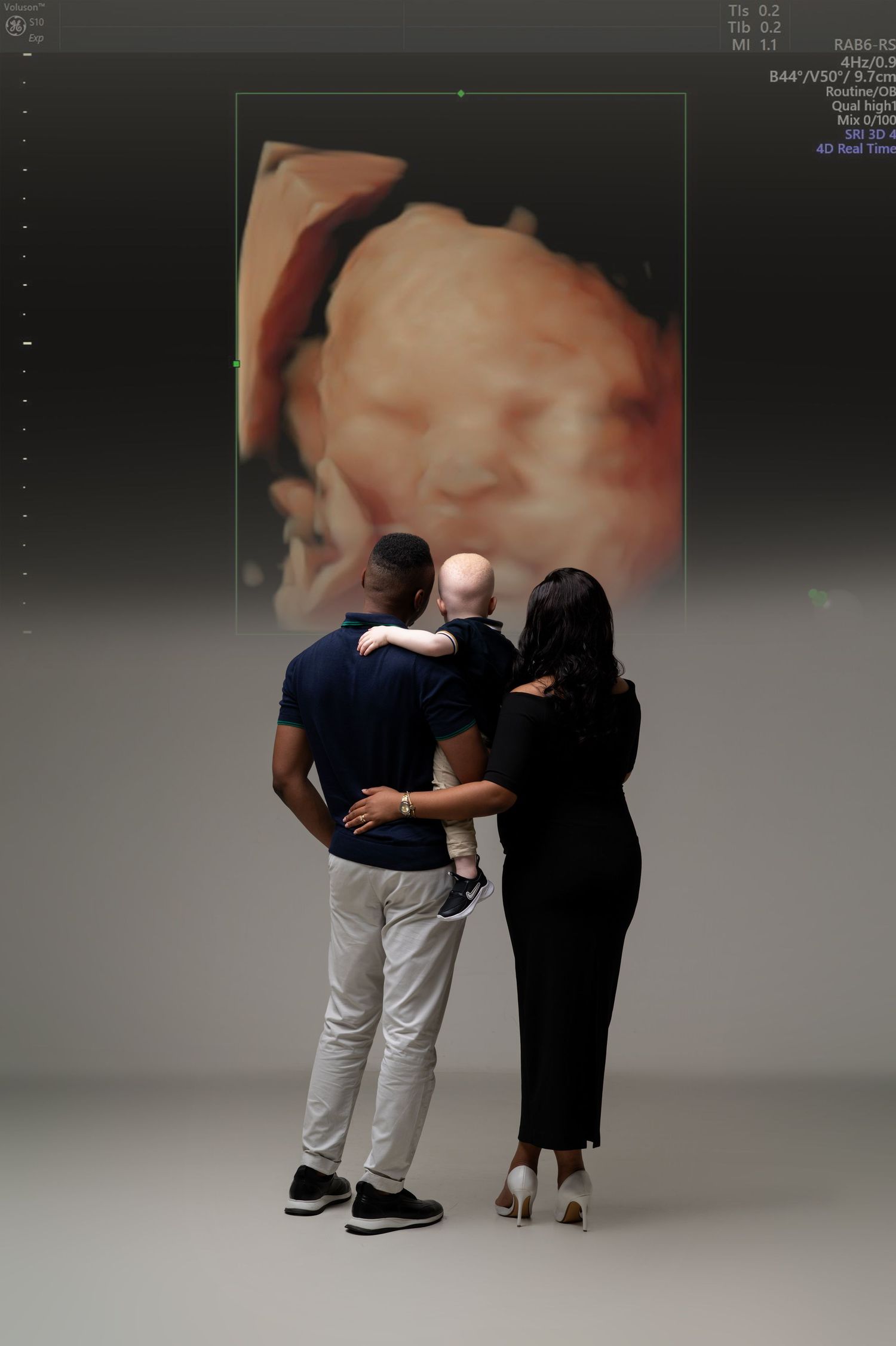 Couple viewing ultrasound image displayed on wall in studio setting.