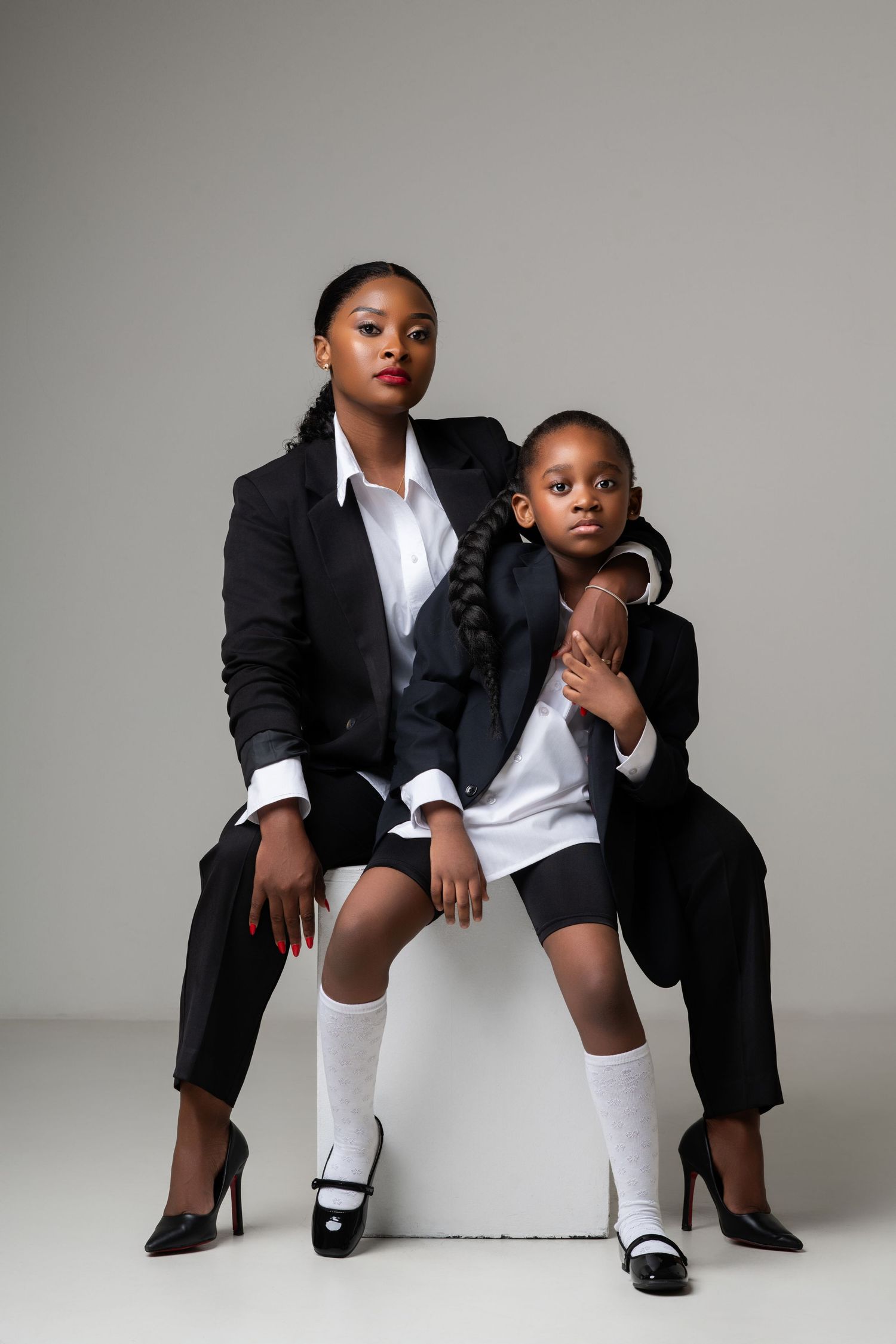 Two people in matching black suits pose for professional studio portrait.