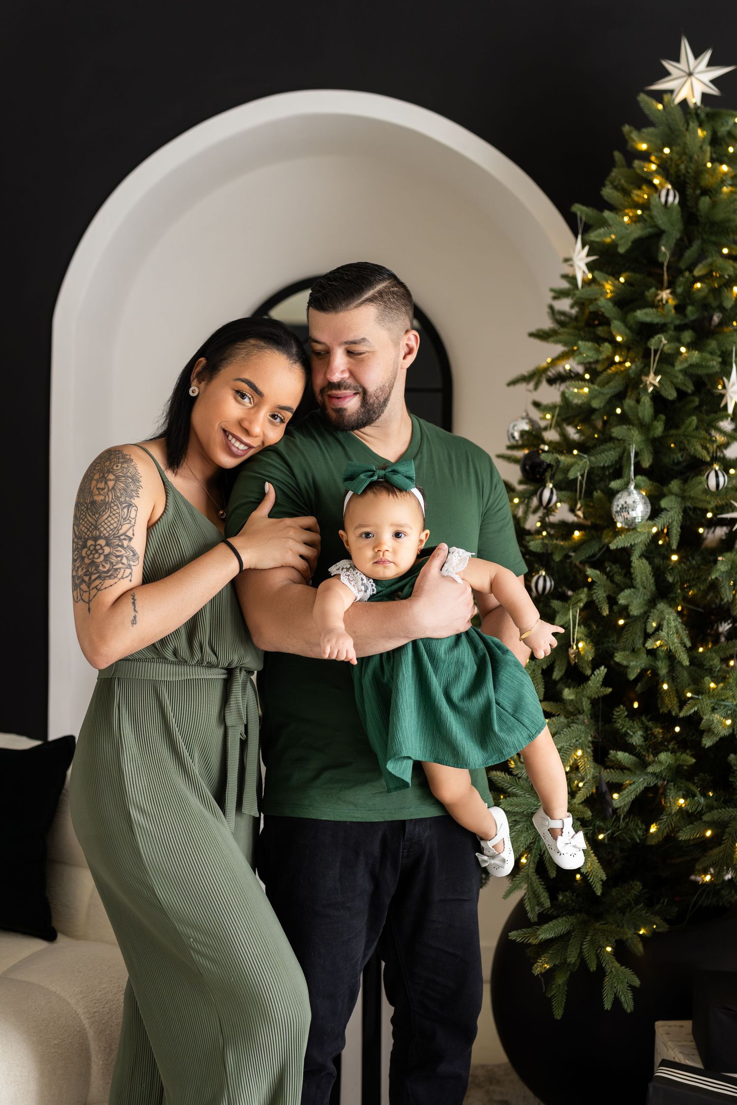 Family holiday photo with Christmas tree and archway in background.