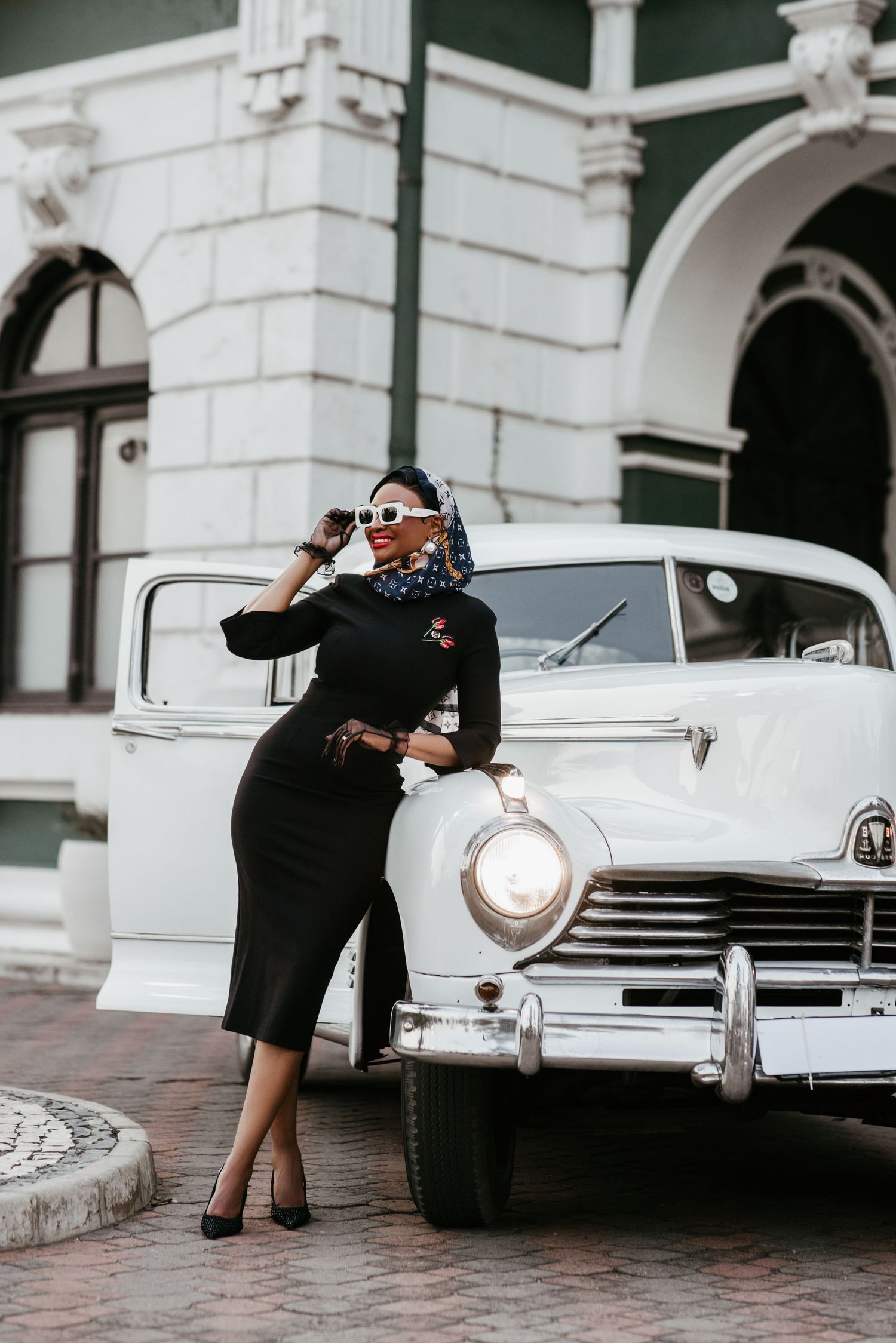 Vintage inspired fashion shoot with classic car and elegant black dress styling.
