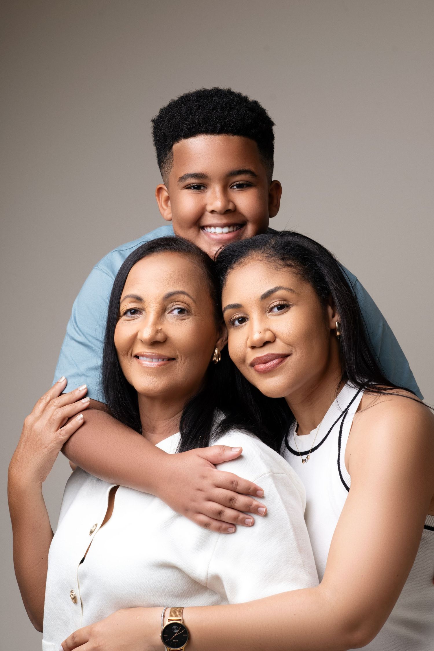 A warm family portrait of loved ones embracing and smiling against a neutral background.