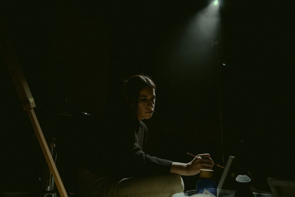 Silhouette working at desk with single spotlight in dark moody setting.