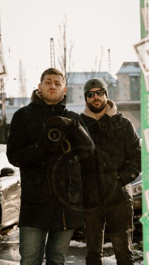 Two photographers in winter gear standing outdoors with camera equipment.