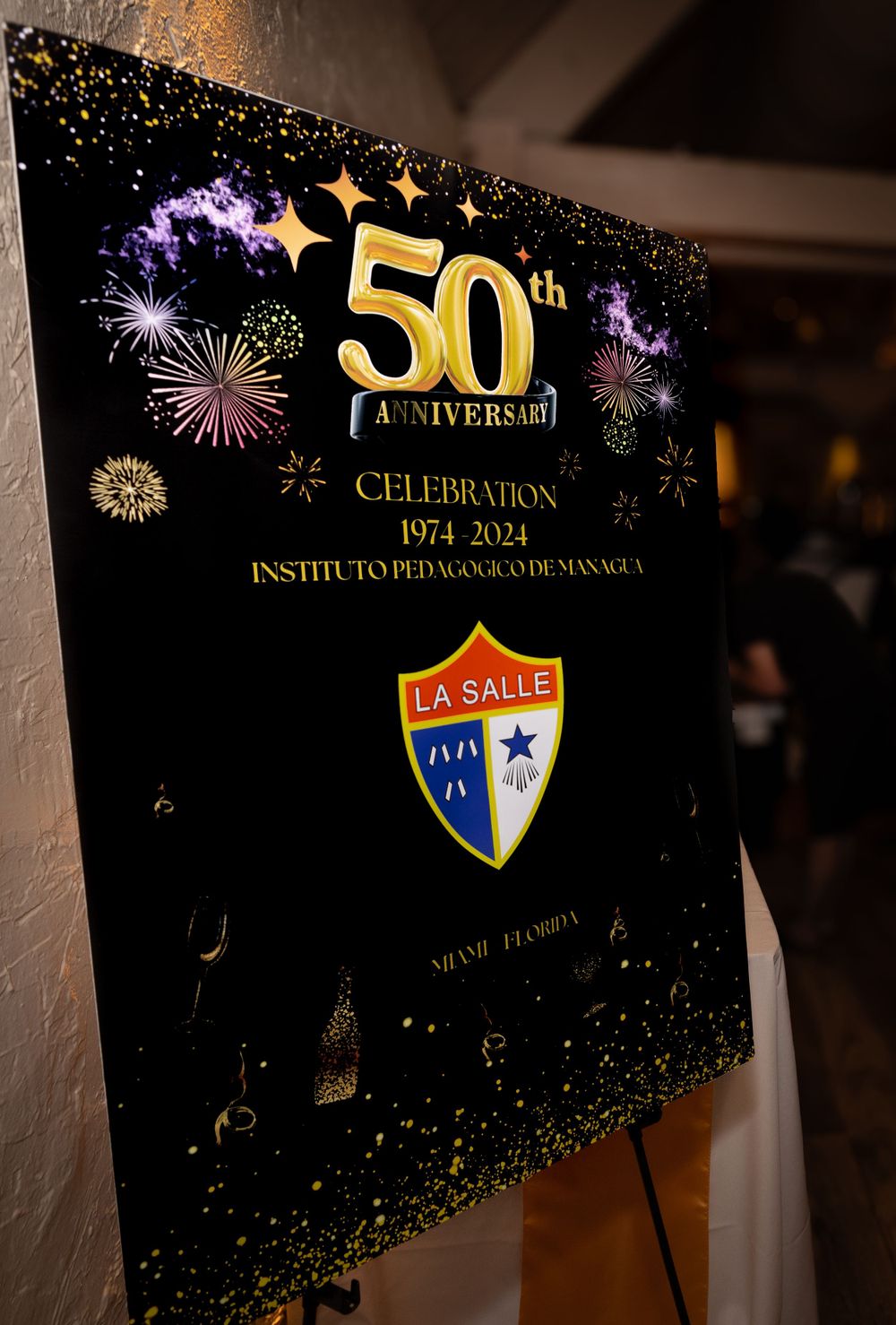 A 50th anniversary celebration banner for La Salle institution features fireworks and the school shield logo on a black background.
