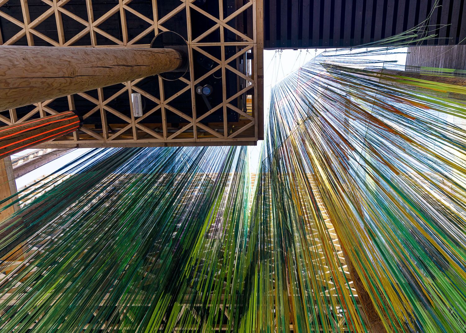 Glass panels in vibrant green and yellow hues create a dramatic architectural pattern stretching upward toward the sky.