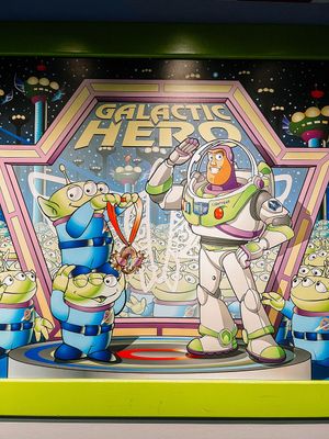 Toy Story themed display featuring Buzz Lightyear with green aliens in a colorful space-themed setting with Galactic Hero text.