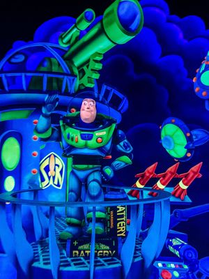 Buzz Lightyear figure illuminated in neon blue and green lights at Disney's Space Mountain attraction.