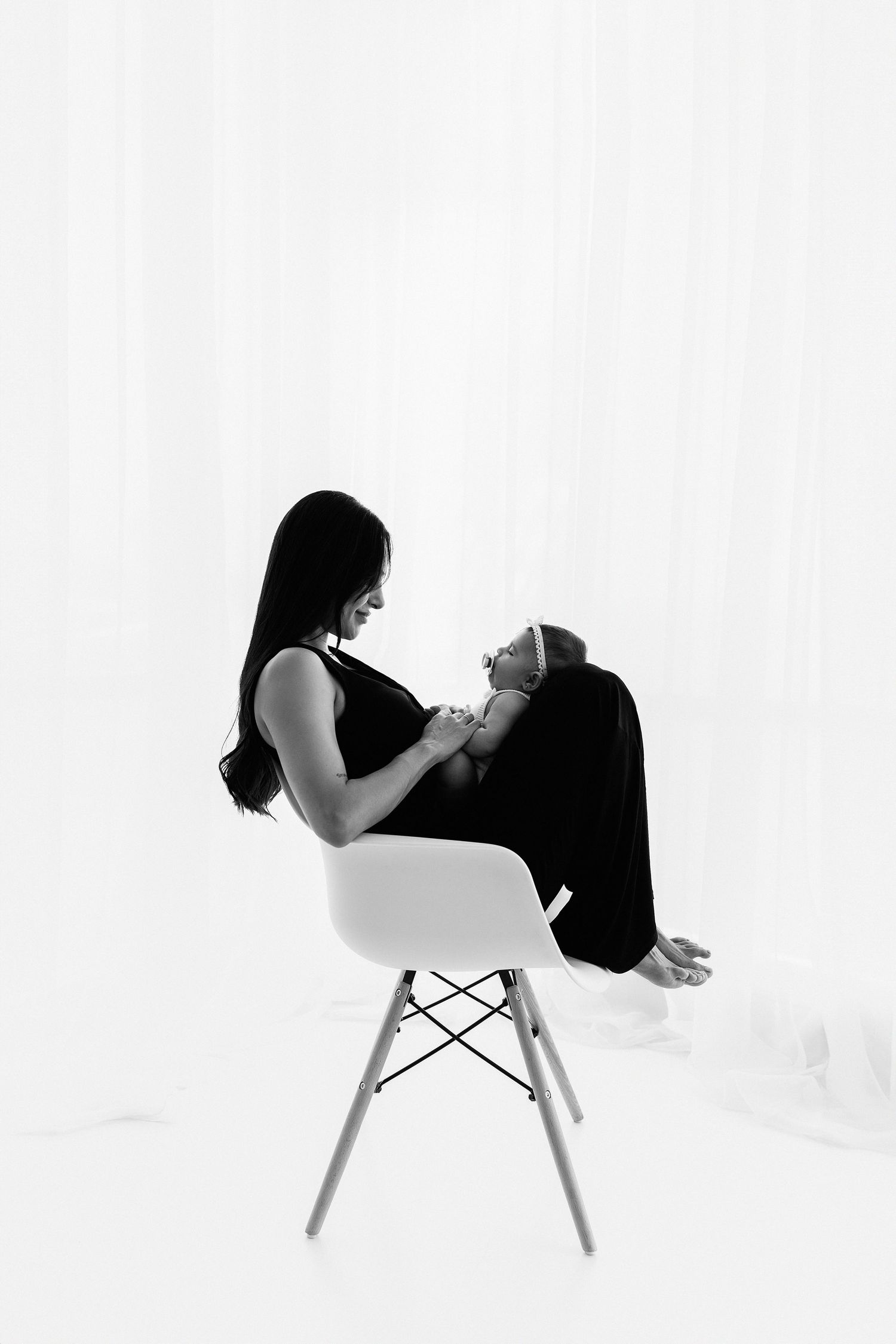 Artistic black and white portrait of parent and child on modern chair.