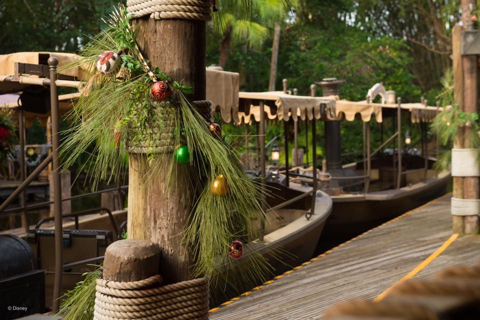 Wooden dock post wrapped with rope and decorated with pine garland and Christmas ornaments at a marina.