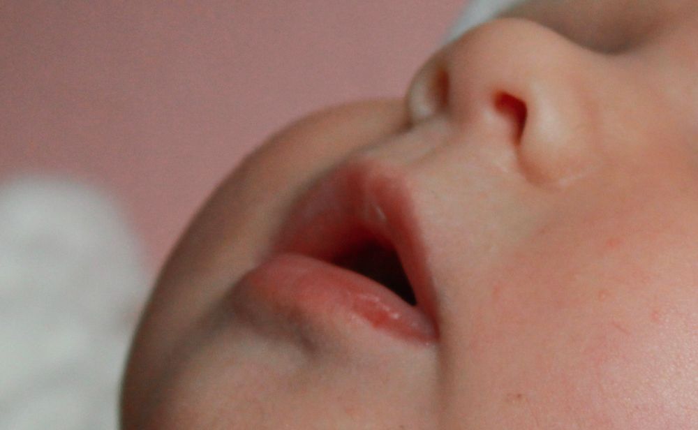 Close-up view of a baby's mouth and nose against a soft background.