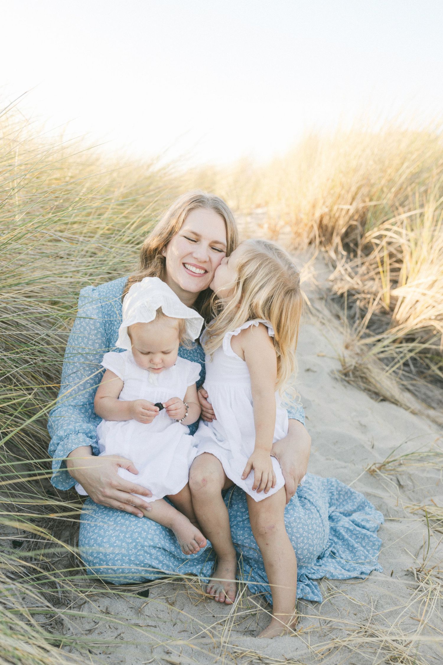 Little girl kissing her mom on the beach captured by Chelsee Rawe Photography