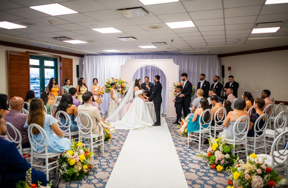 Wedding ceremony setup with white aisle runner and floral decorations in elegant ballroom.