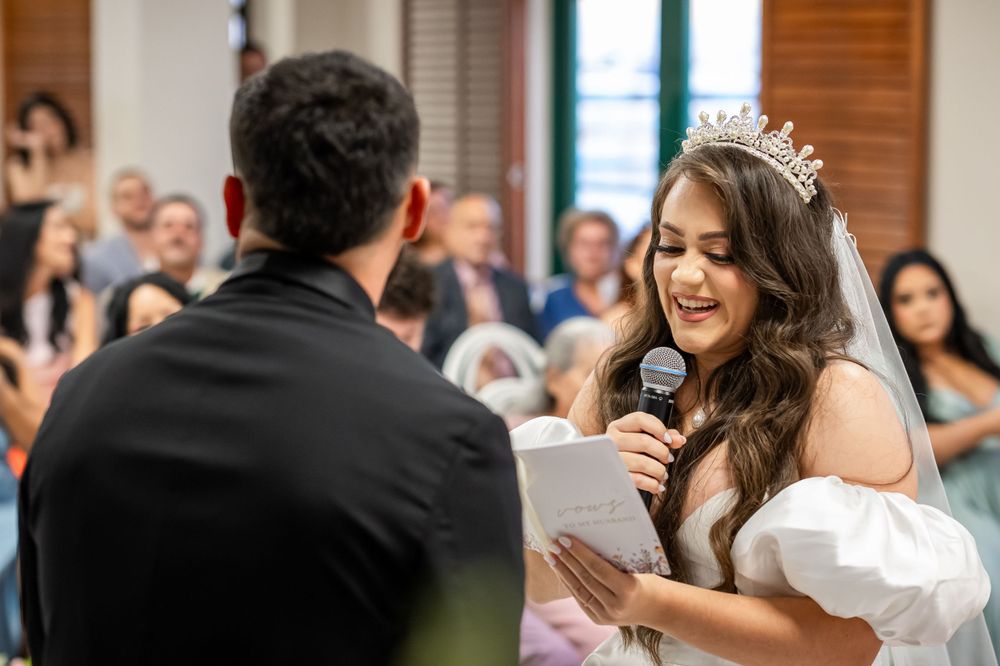 Two people sharing emotional vows during a wedding ceremony with guests in the background.