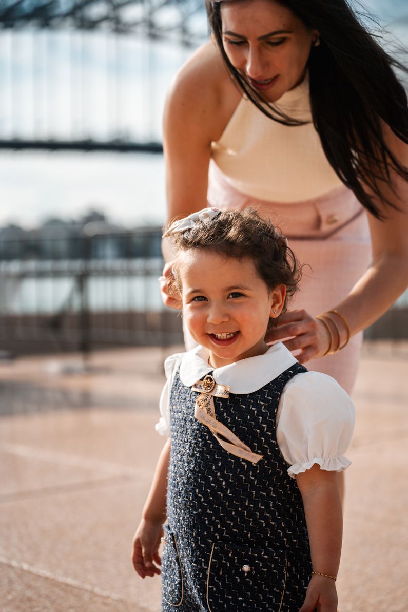 A joyful child laughing as their mom styles their hair during a photoshoot in Sydney, capturing a candid moment