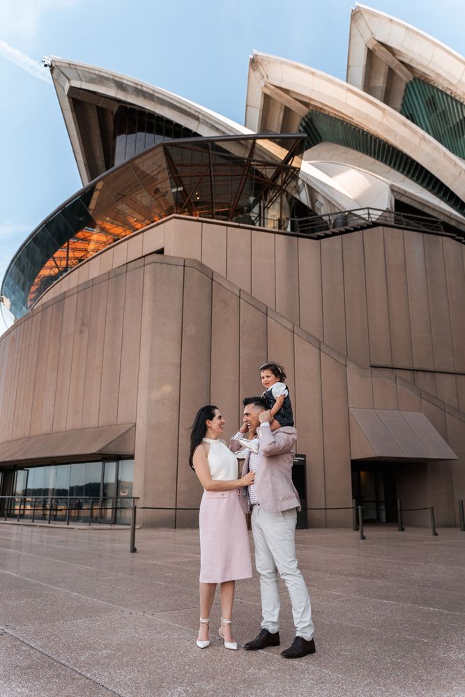 Family of three posing together during a family photoshoot at the Sydney Opera House, showcasing the iconic architecture