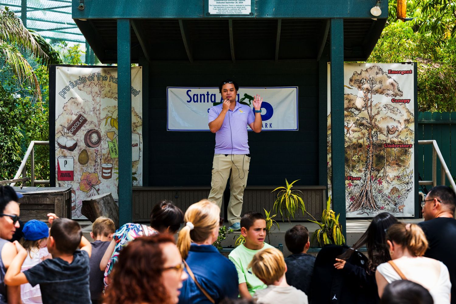 An event photo from Santa Ana Zoo's Party for the planet event. A lady speaks about armadillo's in front of a crowd of adults and kids.