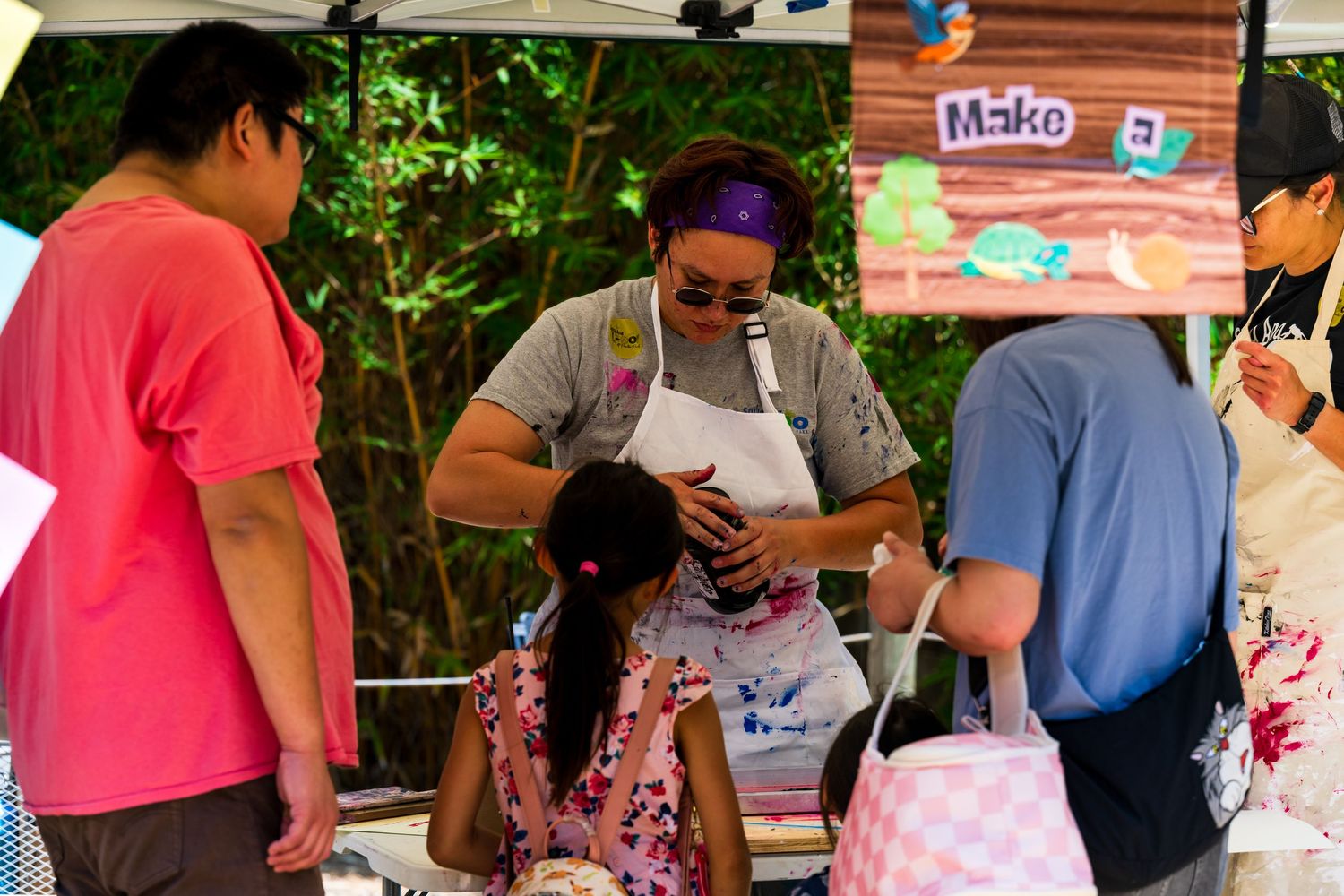 A photo of an employee at the Santa Ana Zoo explaining a hand painting station at the Santa Ana Zoo for their Party for the Planet.