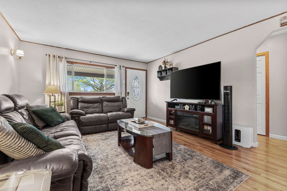 Comfortable living room with leather reclining sectional, hardwood floors, and large flat screen TV.