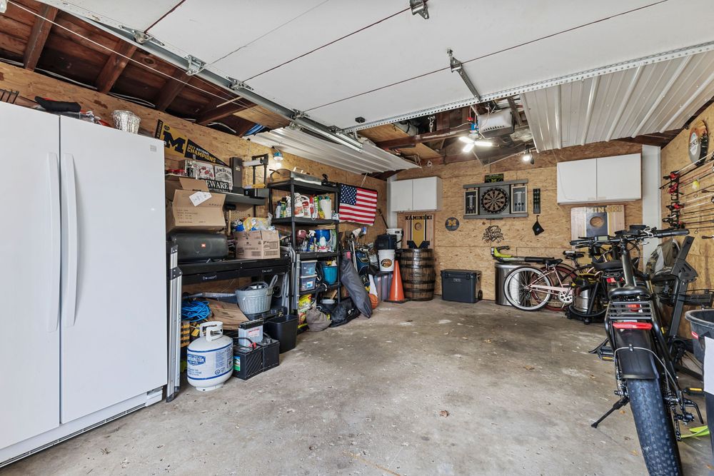 Spacious detached garage interior with shelving, storage items, bicycle, and brick walls with concrete floor.