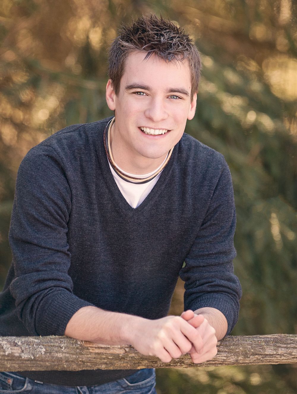 High school senior guy / boy portrait photos at Brighton Recreation area at fence in woods by South Lyon, MI photographer in Brighton
