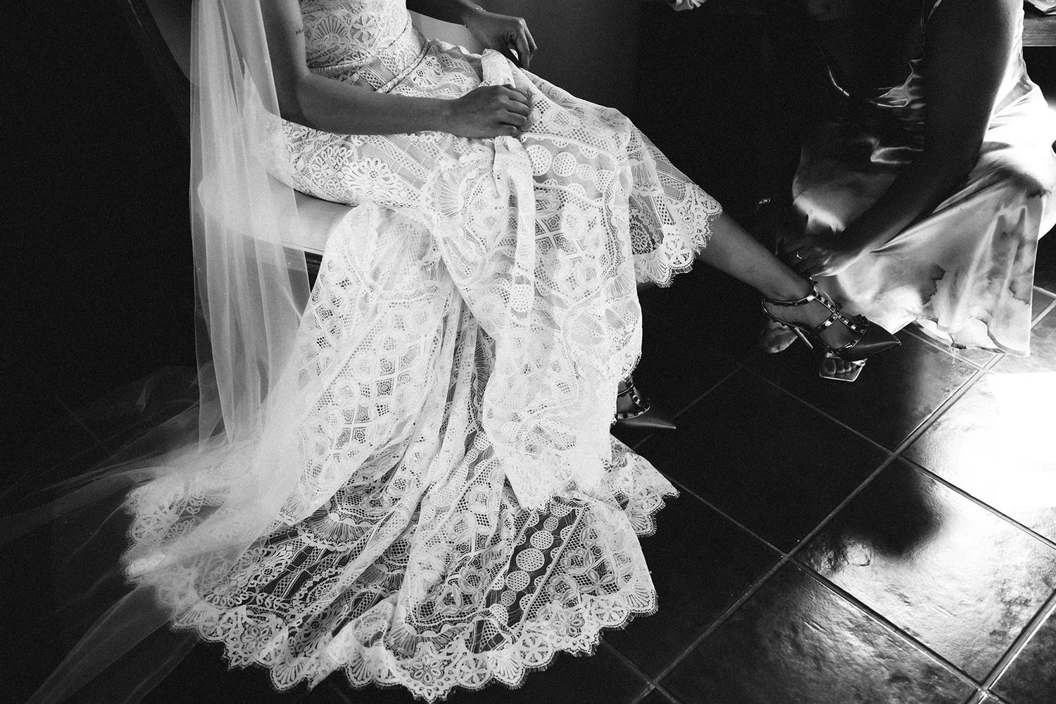 Black and white shots of wedding dress details on wooden floor.
