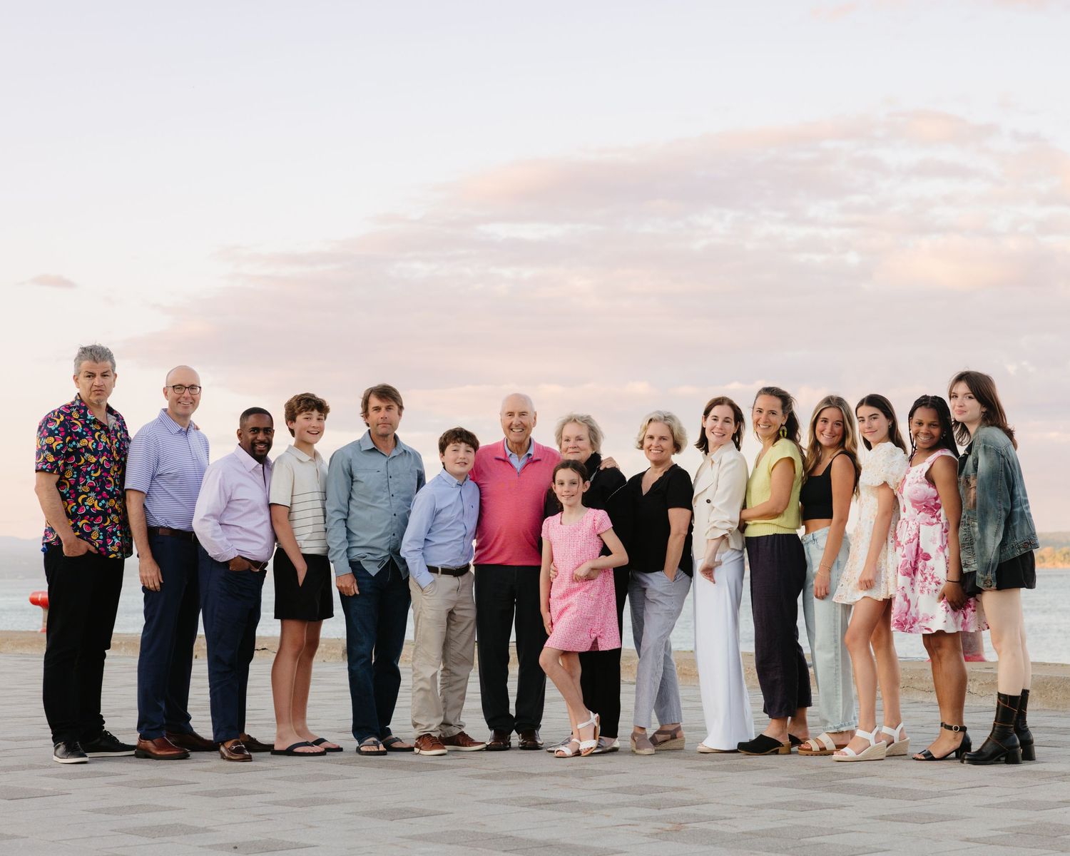 Large family group poses together at sunset for formal portrait by the ocean.