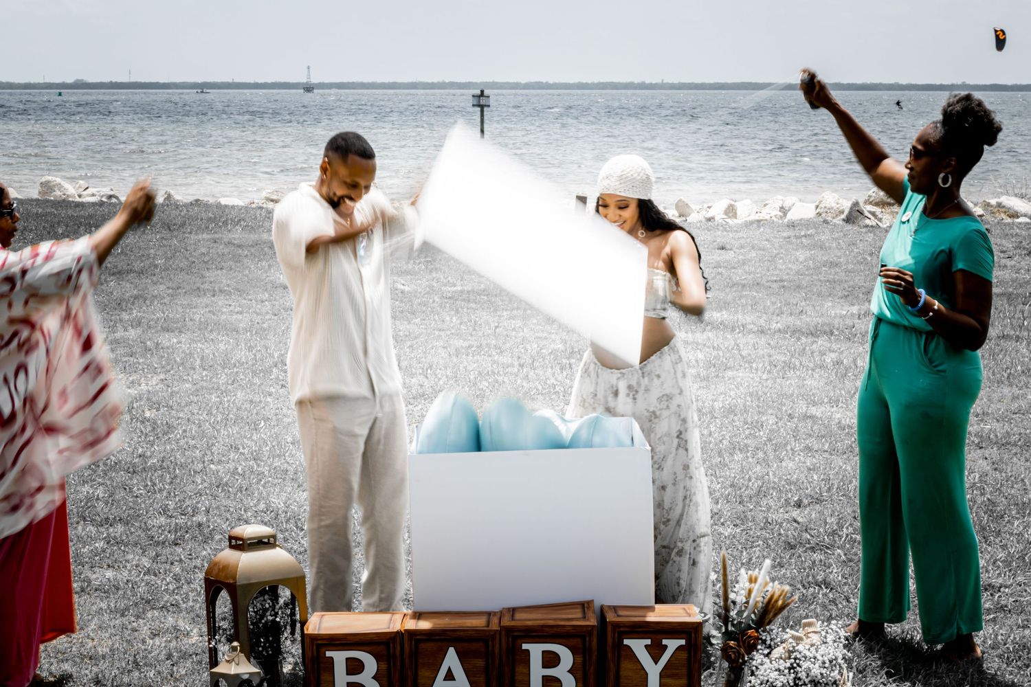 Twin glass beverage dispensers on metal stand with white roses, outdoors at a summer event near the ocean.