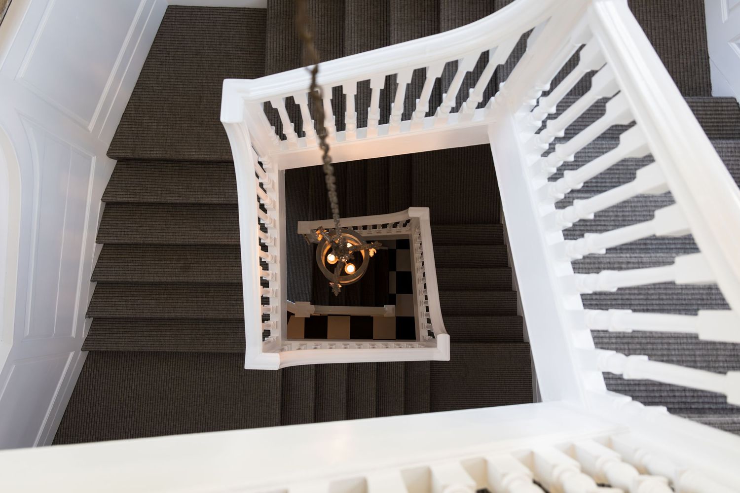 Aerial view of an elegant spiral staircase with white railings and a chandelier.