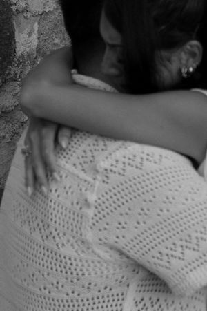 Black and white photo of two people sharing a warm embrace, one wearing a knit sweater.