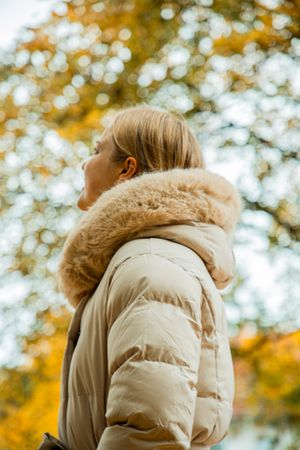 Stimmungsvolles Outdoor-Portrait einer Frau im herbstlichen Park mit warmen Farben und natürlichem Licht.