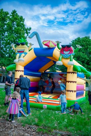 Familienfest mit Hüpfburg und spielenden Kindern auf einer Veranstaltung im Grünen.