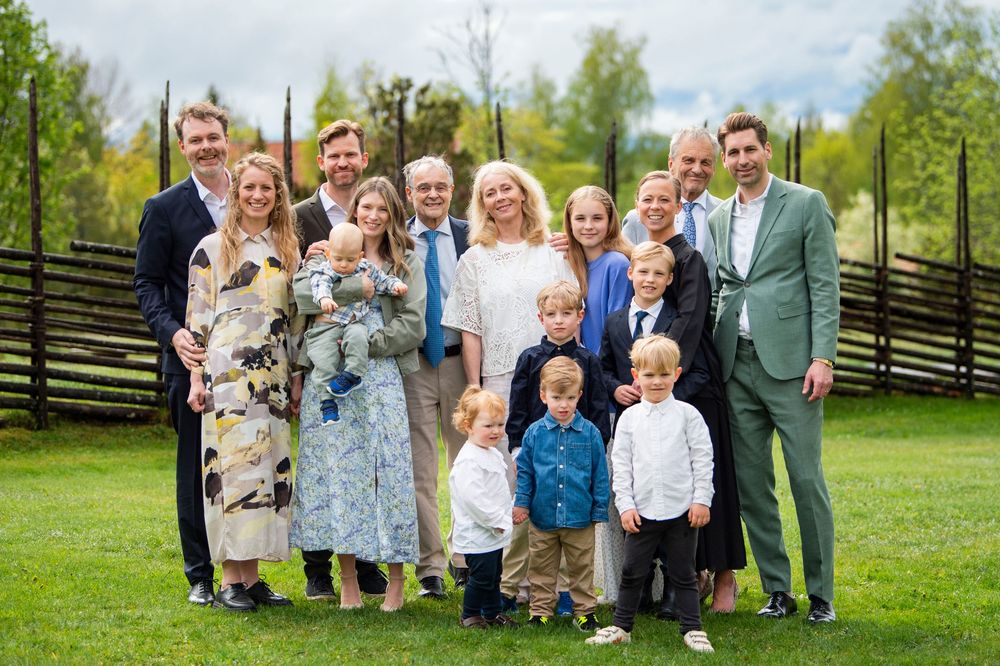 Large multigenerational family posing together outdoors on green grass during a formal celebration.